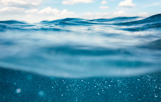 Foto di onde dell'oceano con cielo blu, scattate da dentro l'acqua