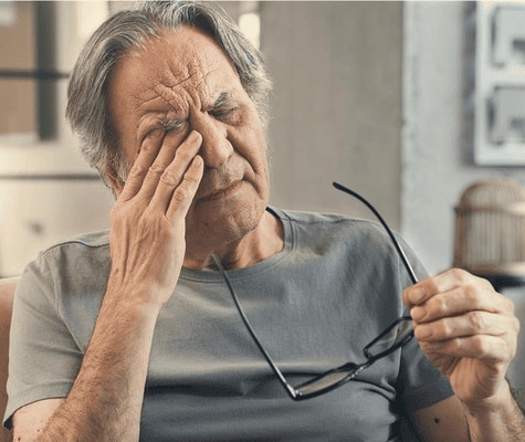  Un uomo anziano che si strofina l'occhio, con un aspetto stanco