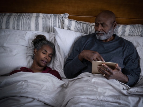  donna che russa a letto mentre il partner sembra infastidito